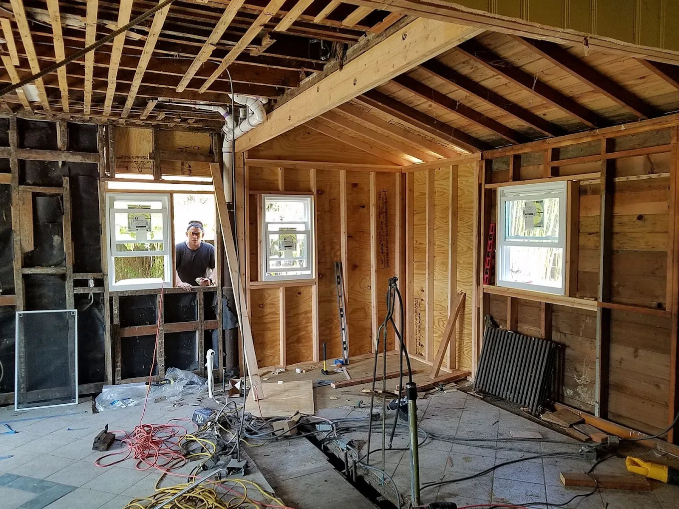 Room opened to the framing with new windows installed and a fresh ridge beam overhead