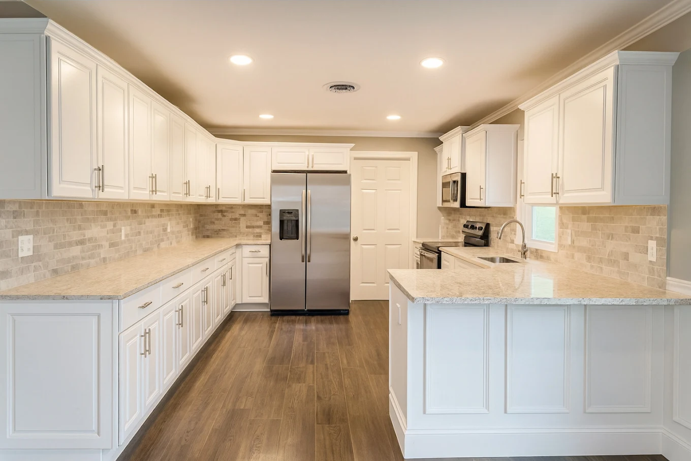 Finished white kitchen with granite counters, stone backsplash and wood-look plank flooring