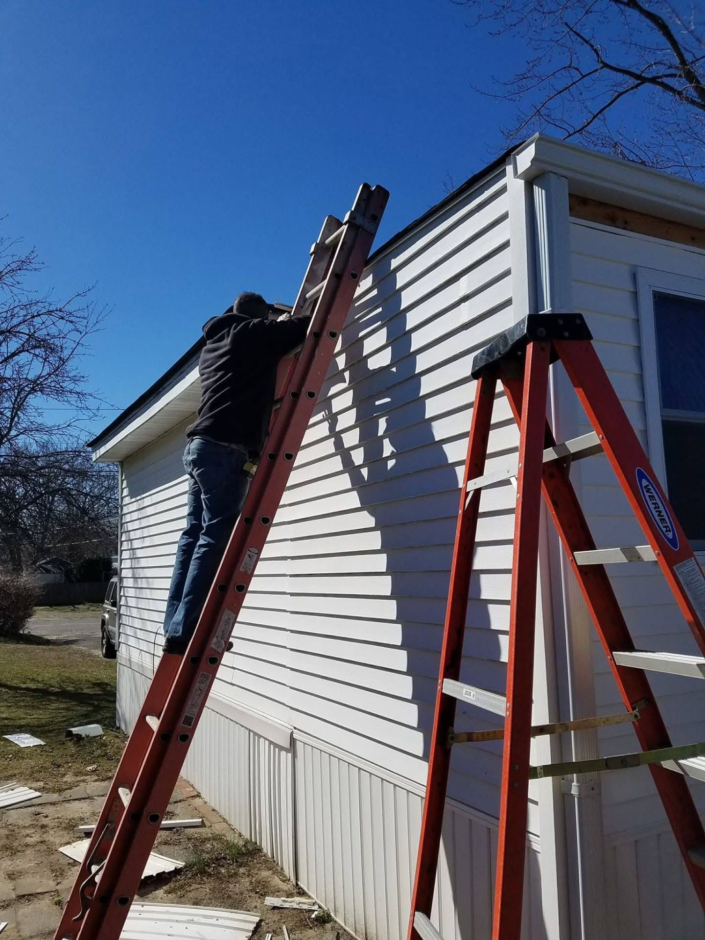 Technician on a ladder installing new siding and trim on a home