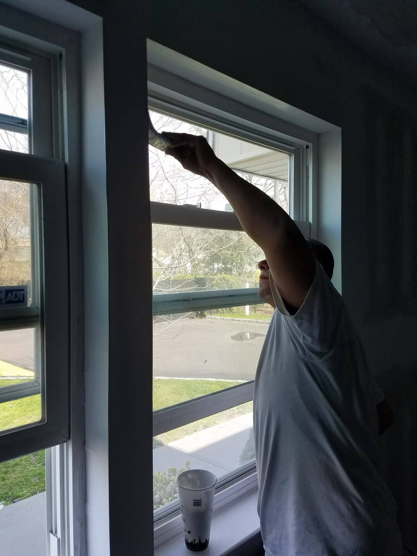Painter cutting in trim around a newly installed double-hung window