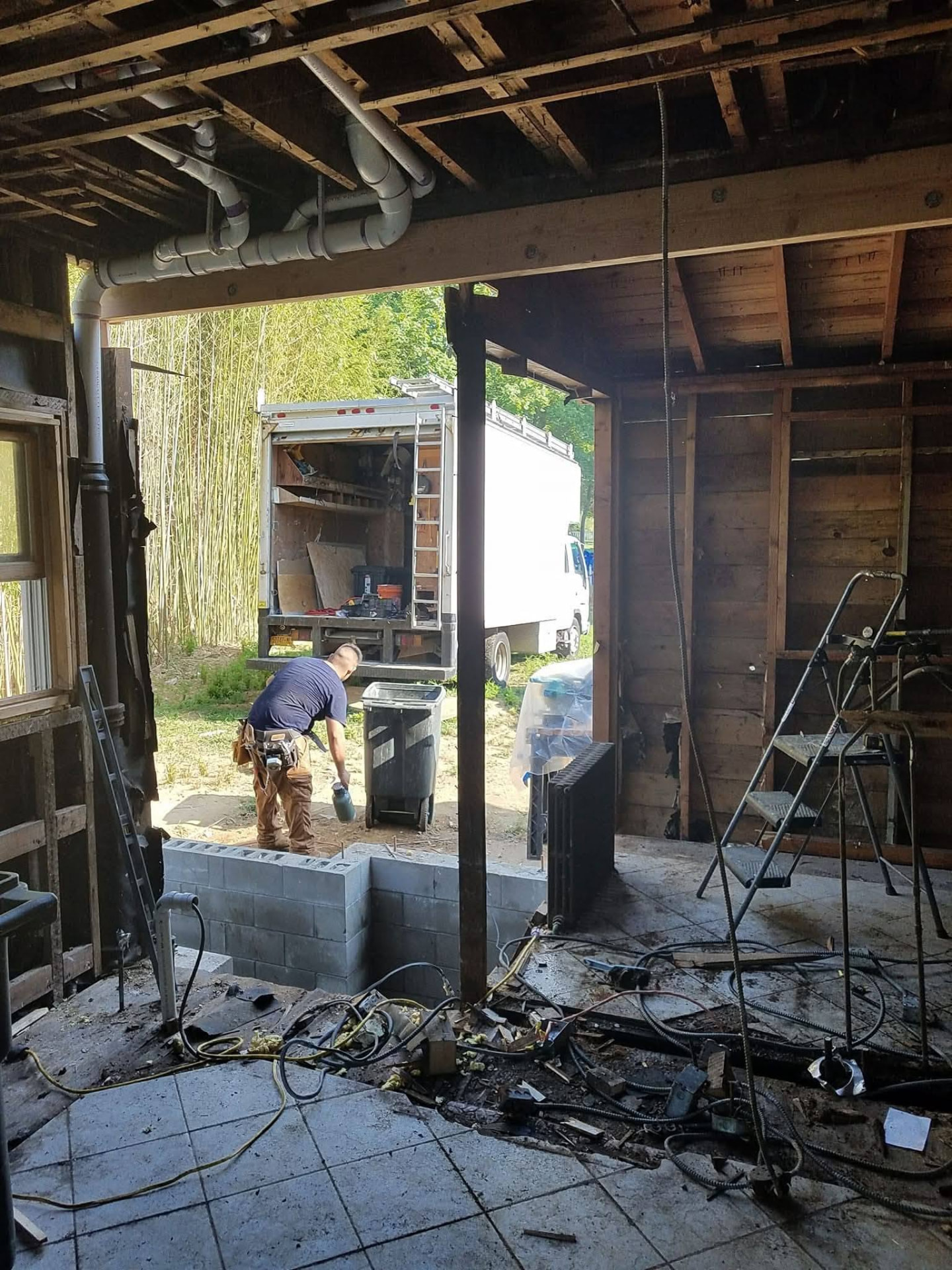 Interior framing opened up with new block foundation wall and rough plumbing overhead